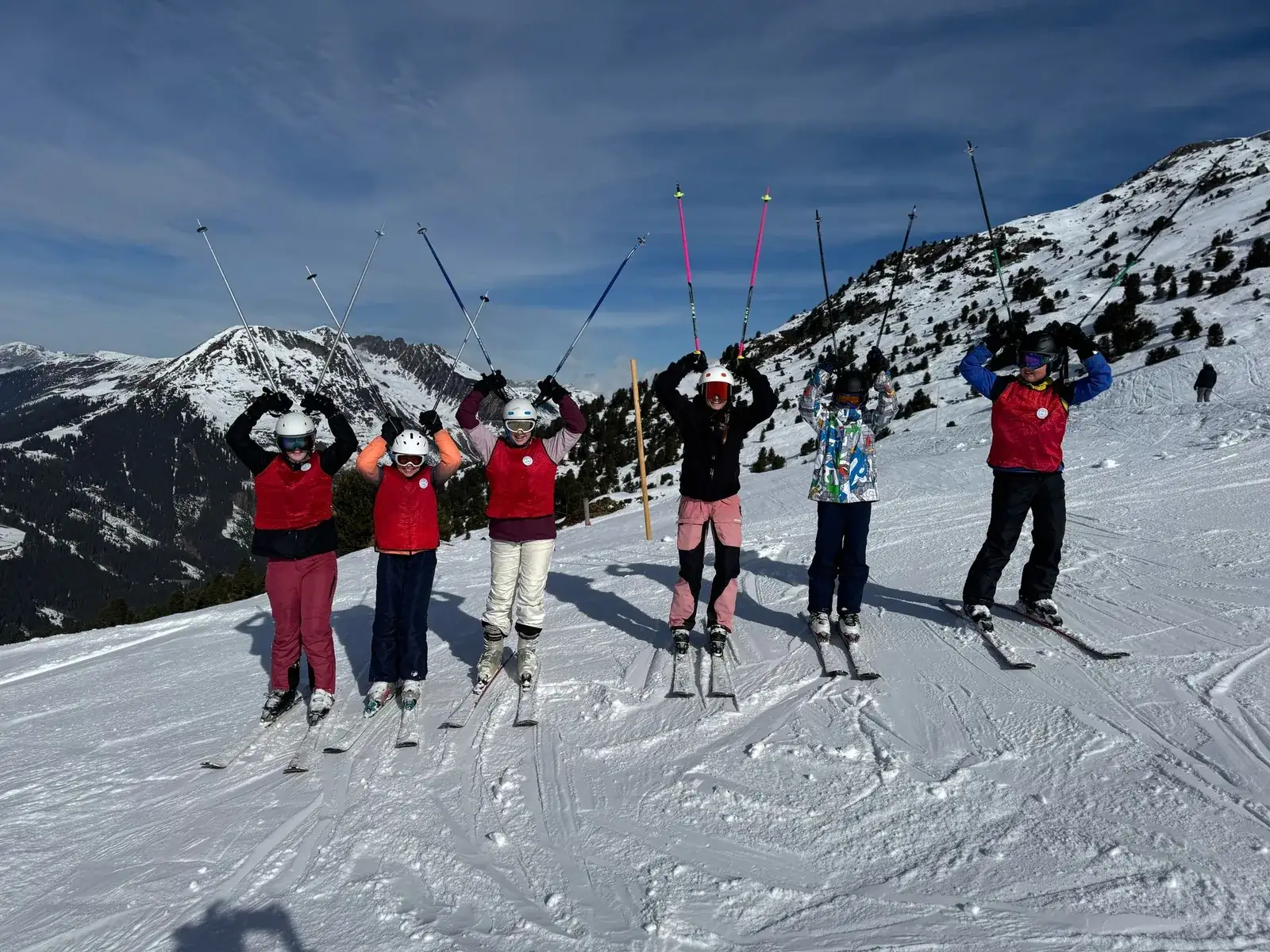 Een groep skiërs op de piste met besneeuwde bergtoppen op de achtergrond