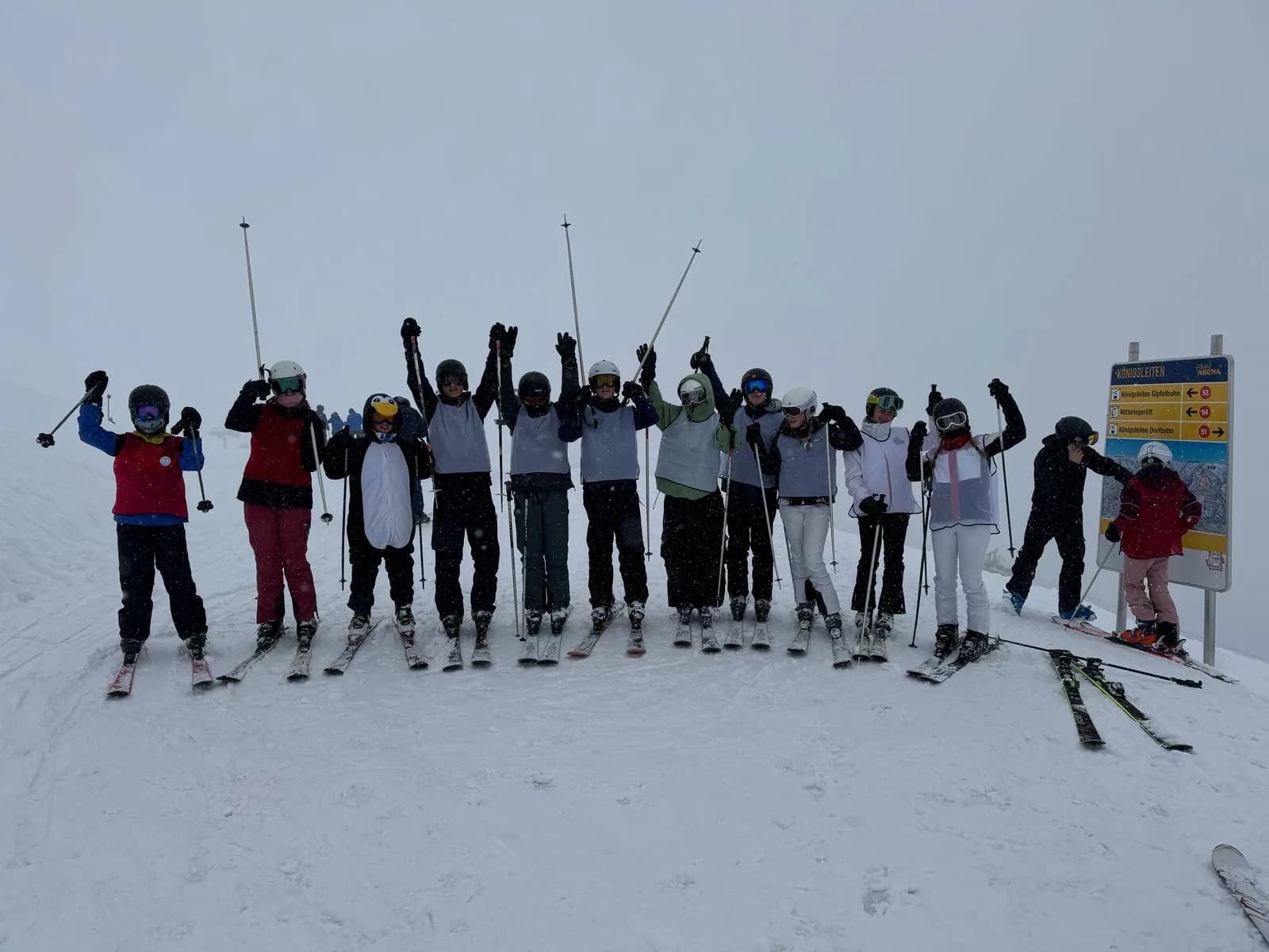 De hele groep staat op een rij op de piste met de armen omhoog