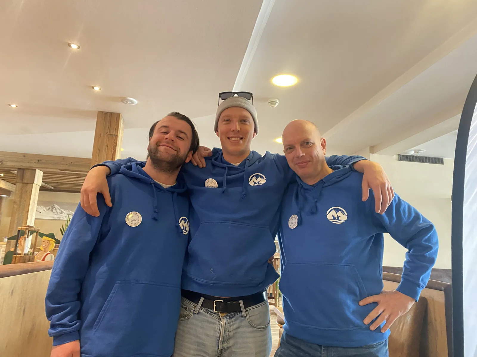 Drie leden van het team in hun blauwe hoodie in de hotellobby