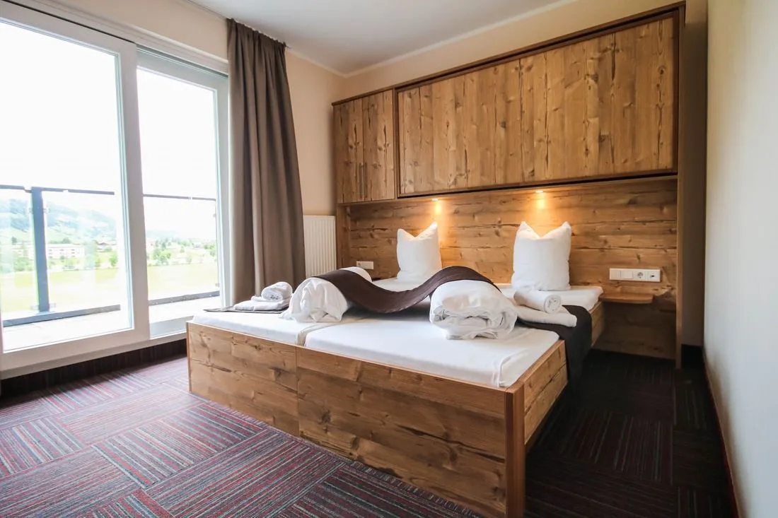 Hotelkamer met houten bedden en een balkon met uitzicht op het dal