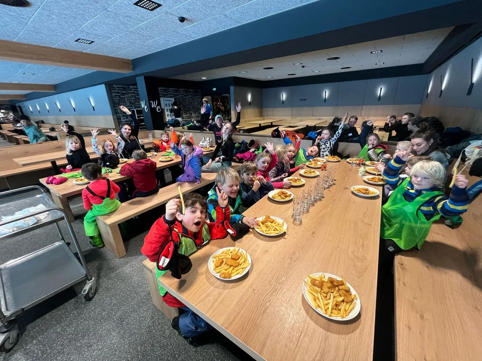 Kinderen lunchen samen aan een lange tafel in het bergrestaurant