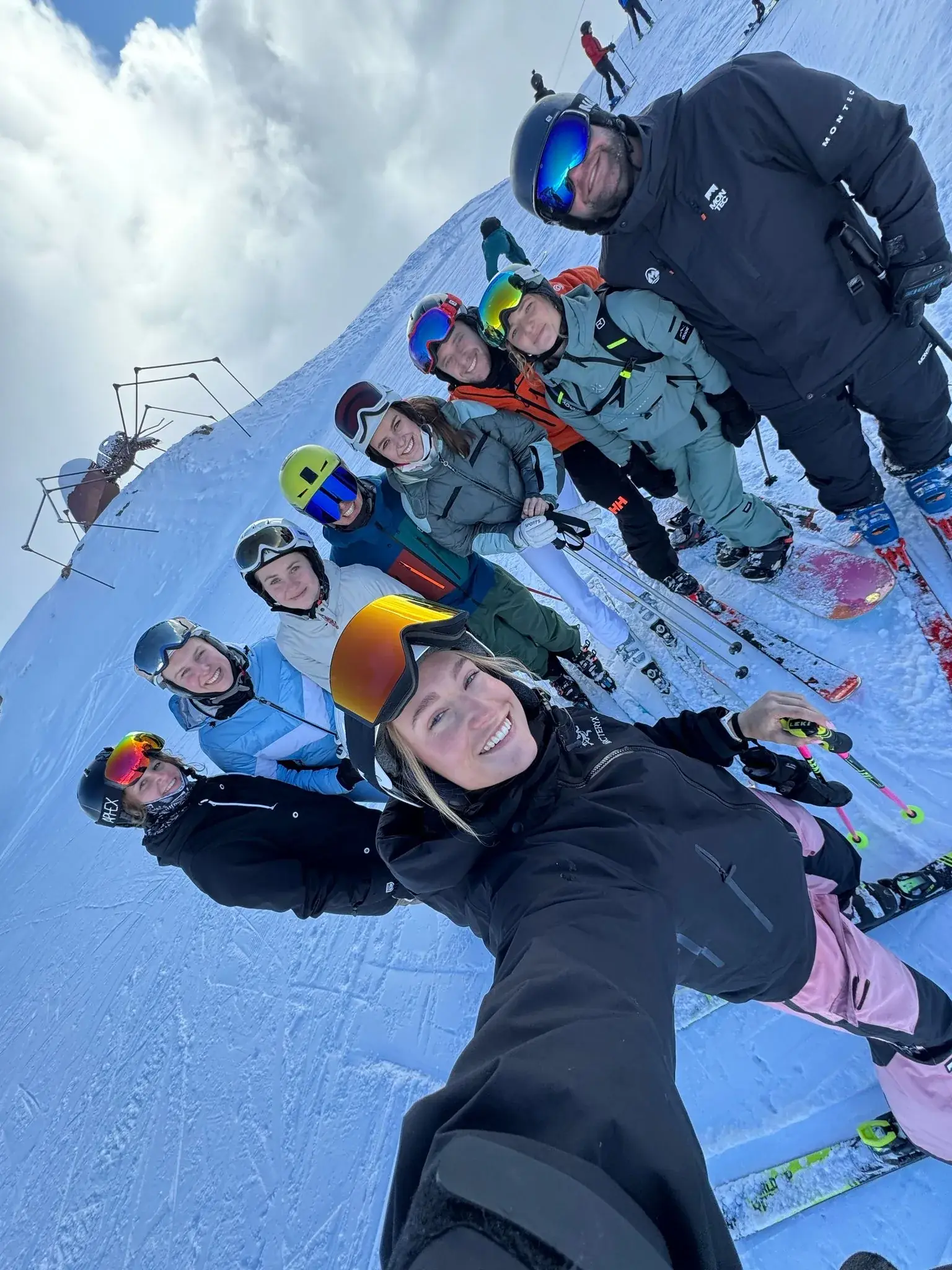 Een skileraar maakt een selfie met zijn hele skigroepje op de piste